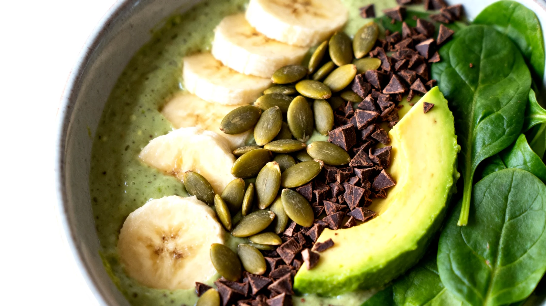 Smoothie bowl con avocado, banana, spinaci, semi di zucca e cacao crudo"